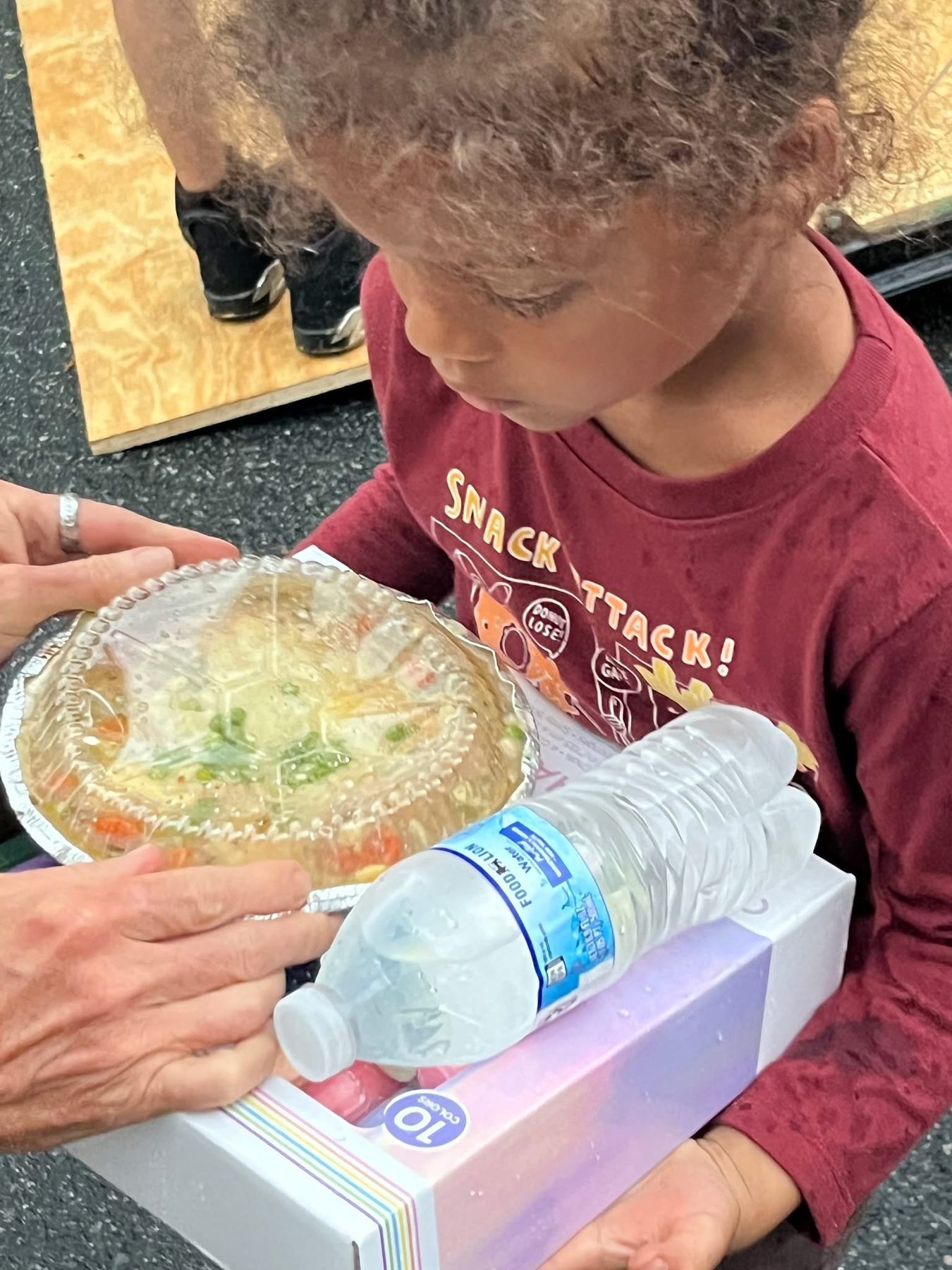 A child receiving a hot meal and a bottle of water on the street